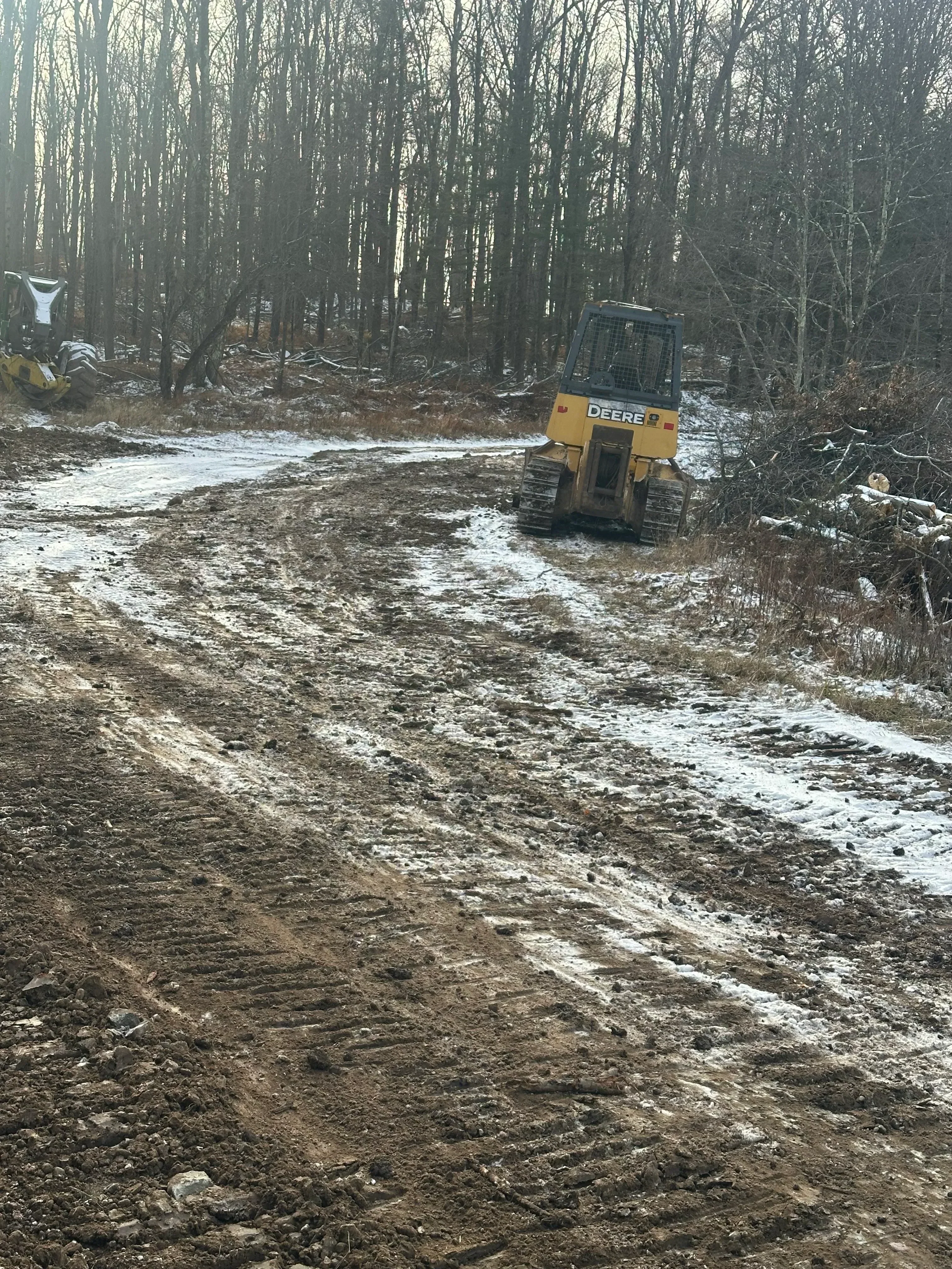 Yellow excavator on graded driveway with exposed soil and rock surface